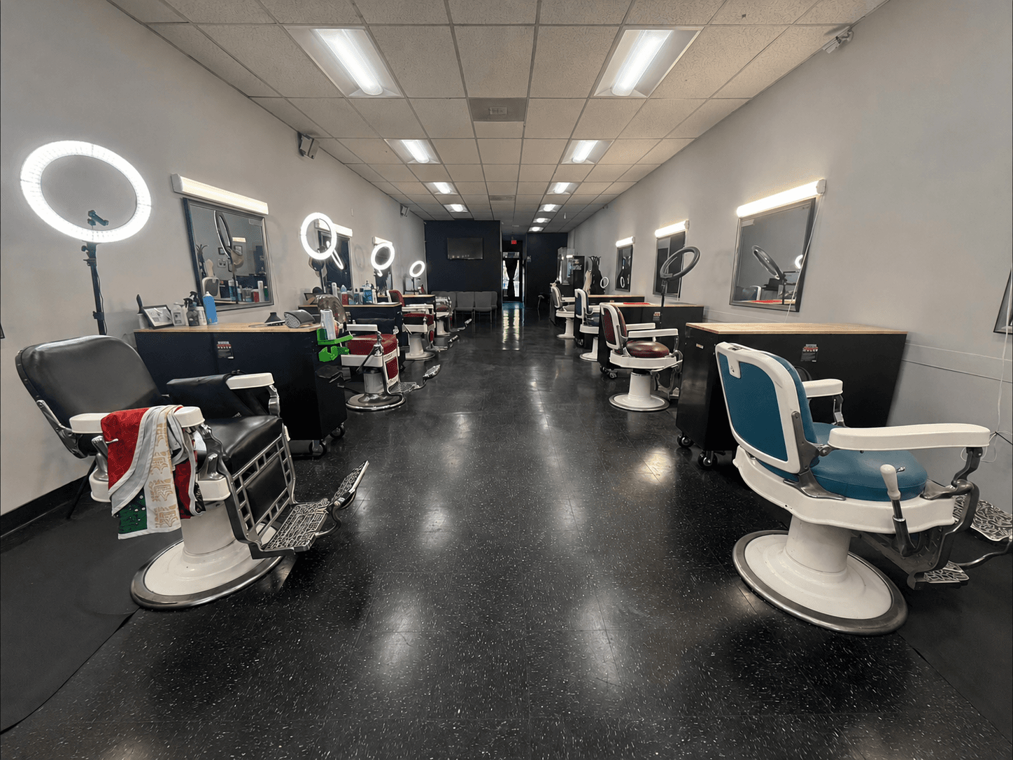 Row of vintage barber chairs, ring lights, and mirrors inside Standard Barbershop Inc